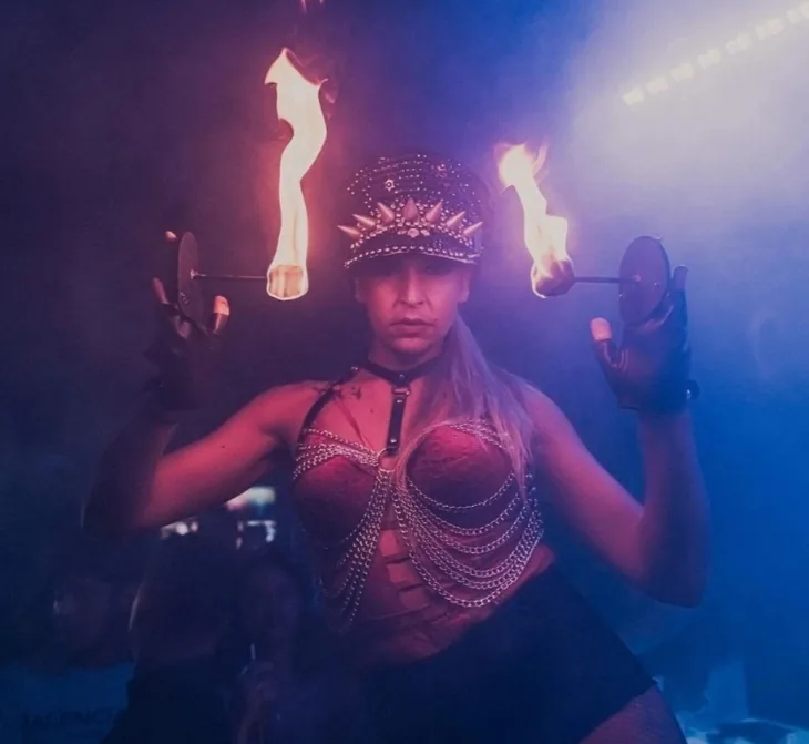 Artiste de feu coiffée d'une couronne, torches allumées dans chaque main