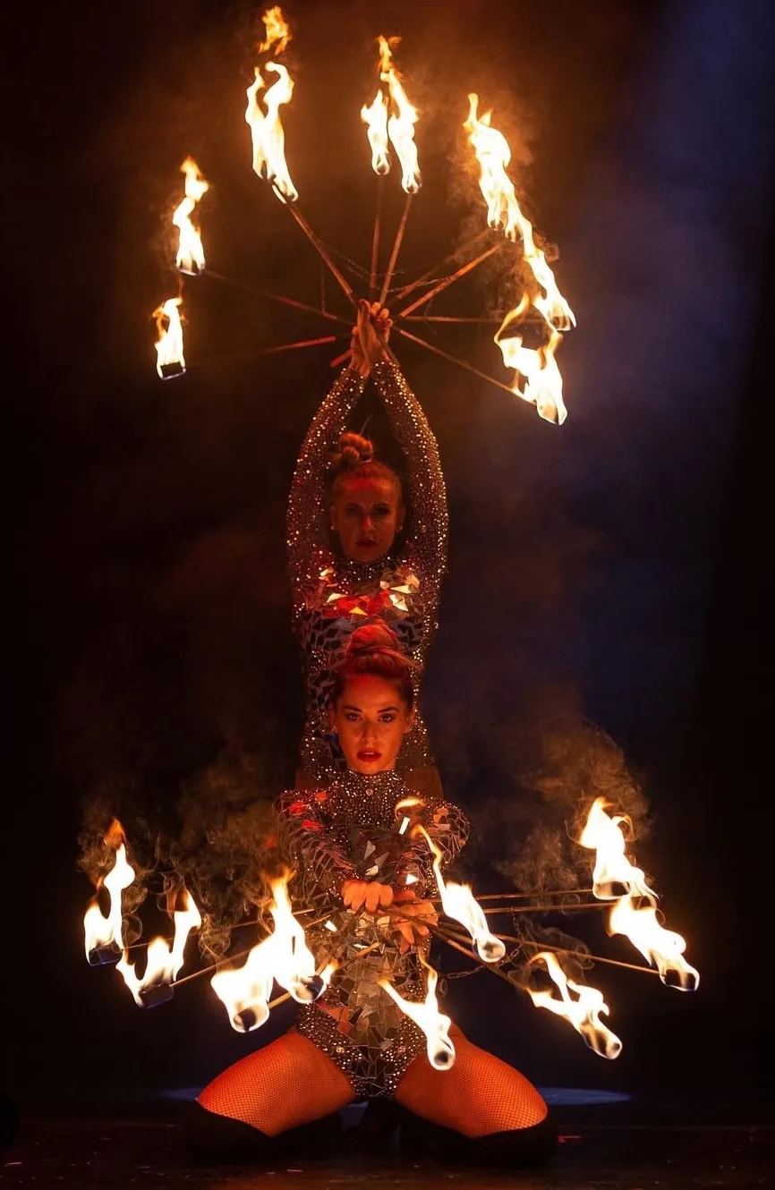 Deux artistes de feu déployant des éventails de flammes sur scène