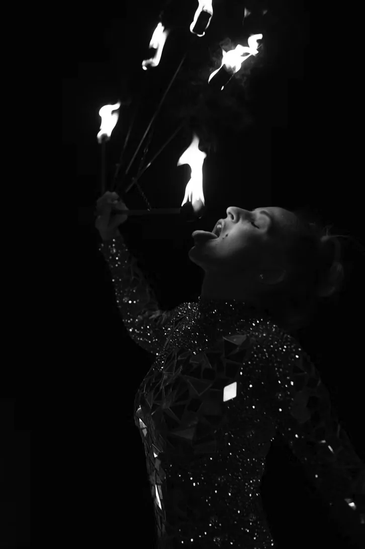 Artiste cracheuse de feu en combinaison à sequins, photographiée en noir et blanc